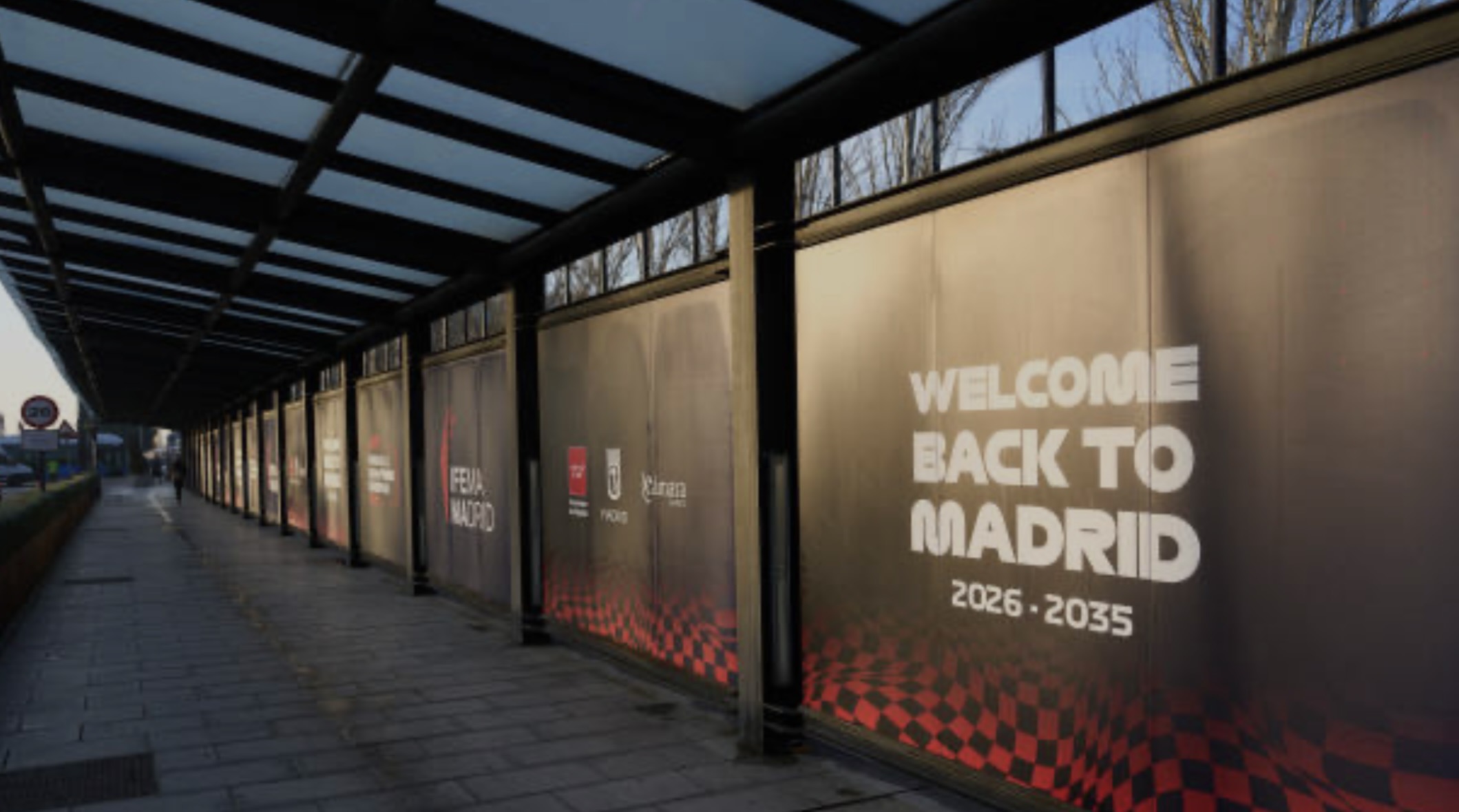 An evening walkway beside IFEMA Madrid with illuminated panels reading Welcome Back to Madrid, 2026–2035.